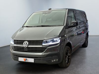 La camionnette grise est garée dans une grande pièce au sol noir.