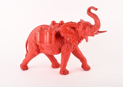un petit éléphant rouge avec une selle sur le dos
