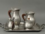 a silver tray with two silver pitchers and a cup on it