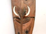 a wooden mask hanging on the wall on the wall
