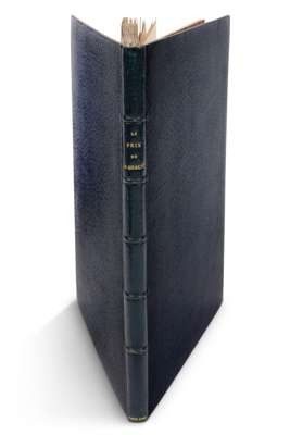 an old book with a black cover sitting on top of a white surface