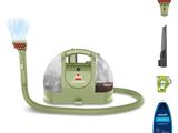 l'aspirateur est vert et est équipé d'un tuyau et d'un vaporisateur