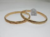 pair of gold tone bangles with engraved design on each side