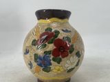 a small vase with flowers painted on it on a white surface