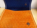 un coussin de chaise orange et bleu posé sur une table en bois