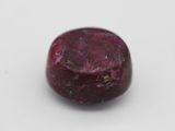 a close up of a red stone on a white surface