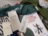a pile of clothing and a book on a bed