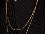 a woman wearing a black dress and a gold chain necklace