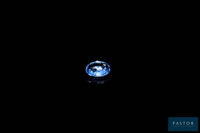 a blue diamond in the dark with a reflection on the surface