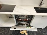 a cat hiding under a dishwasher in a kitchen