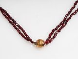 a close up of a red beaded necklace on a white surface