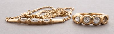 two gold rings and a gold chain on a gray surface