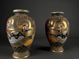 two vases with designs on them sitting side by side on a black surface