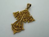 a gold cross pendant with filigrees on a white background