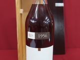 la bouteille de vin se trouve à côté d'une boîte en bois, posée sur une surface rouge
