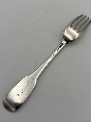 une cuillère et une fourchette posées sur une table blanche, sur fond blanc