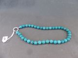un gros plan sur un collier de perles turquoise muni d'un fermoir en argent