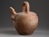 a brown vase with a handle on a gray surface