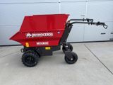 un petit camion-benne rouge garé devant un garage