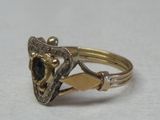 une image montrant un gros plan d'une bague en or sertie d'une pierre noire