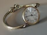 une montre en argent, attachée à une chaîne, posée sur une table
