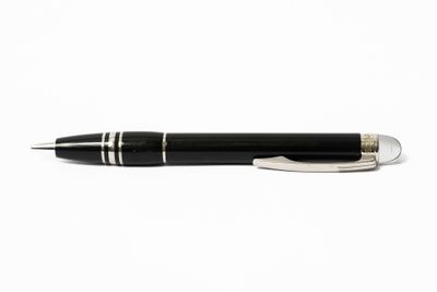 le stylo est noir avec des finitions argentées et repose sur une surface blanche