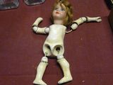 une poupée posée par terre à côté d'autres objets