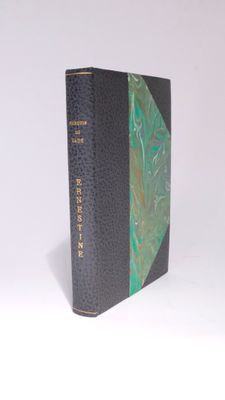 an old book with a green cover sitting on top of a white surface