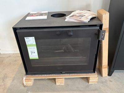 un four noir posé sur une palette dans une pièce