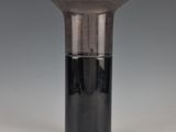 a glass vase with a black base sitting on a table
