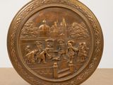 an image of a bronze plate with a scene of people in a park