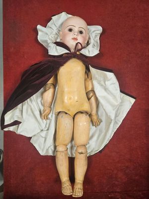 painting of a wooden doll with a cape and bonnet on a red background