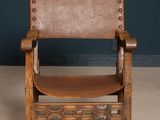 an old wooden chair with a leather seat in front of a blue wall