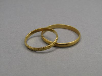 deux alliances en or posées sur une surface grise