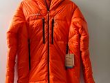 une doudoune orange accrochée au mur, avec une étiquette dessus
