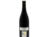 the bottle of red wine is sitting on a white surface