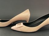 beige pumps with a bow on the toe on a black surface