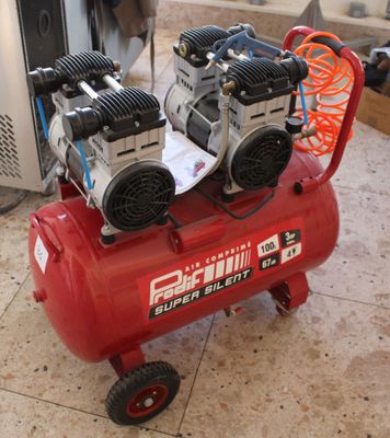two air compressors sitting on top of a red cart