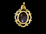 an image of a gold pendant with a purple stone in the center