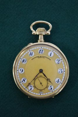 une montre de poche en or posée sur un tissu vert