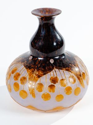 un vase noir et or posé sur une surface blanche