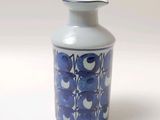 un vase bleu et blanc posé sur une surface blanche