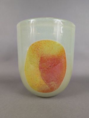 a glass cup with a peach on it sitting on a table