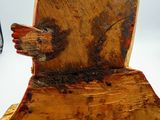a wooden bird that is sitting on a piece of wood