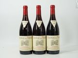 trois bouteilles de vin rouge posées sur une table blanche