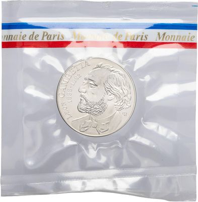 the coin is in a clear plastic bag with a red, white, and blue ribbon