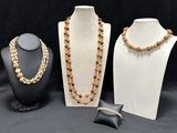 three different necklaces and bracelets on display on a black background