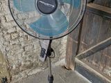 un ventilateur posé sur un support devant un mur de briques