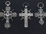 three silver crosses on a black background, one with a cross and the other with a cross on it