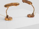 two gold desk lamps on a white surface with a white background
